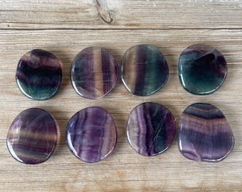 Puede incluir: Ocho piedras de fluorita pulidas en varios tonos de morado, verde y blanco. Las piedras son lisas y tienen una forma natural y orgánica.