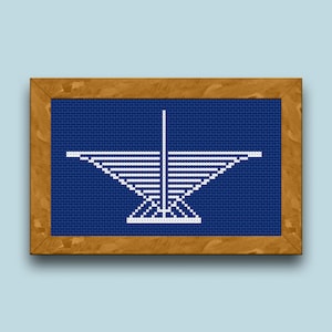 May include: A framed blue and white cross-stitch design of a stylized white star with a central point. The star is set against a dark blue background.