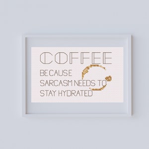May include: A framed cross-stitch design with the text "COFFEE BECAUSE SARCASM NEEDS TO STAY HYDRATED" and a brown coffee stain.