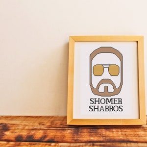 Può includere: Una stampa incorniciata con un'illustrazione di cartone animato di una persona con occhiali da sole e barba. Il testo "SHOMER SHABBOS" è stampato sotto l'illustrazione.