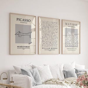 Puede incluir: Tres impresiones artísticas enmarcadas. La primera presenta un dibujo de Picasso, la segunda un diseño floral de William Morris y la tercera un diseño floral de Matisse. Las impresiones se muestran sobre un sofá blanco con cojines decorativos.