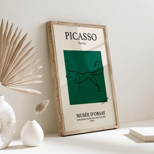 Puede incluir: Impresión artística enmarcada con un dibujo lineal minimalista de un zorro sobre un fondo verde oscuro. La impresión incluye el texto "PICASSO The Fox" y "MUSÉE D'ORSAY PARIS" en un marco de madera. La obra de arte se exhibe sobre una superficie blanca.