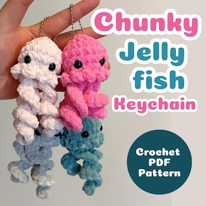 May include: Three handmade crochet jellyfish keychains in white, pink, and teal. Each jellyfish has black button eyes and a spiral body. The image includes text that reads "Chunky Jellyfish Keychain" and "Crochet PDF Pattern".