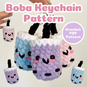 May include: A collection of crocheted boba tea keychains in pastel shades of pink, blue, and purple. Each keychain has a smiling face and black boba pearls. The text "Boba Keychain Pattern" is displayed above the keychains.