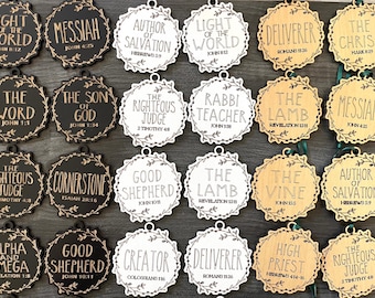 May include: Assortment of round wooden ornaments with various religious phrases and Bible verses, such as "Light of the World" and "Messiah." Each ornament has a decorative floral border and a small hole for hanging.