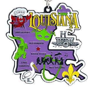 May include: A purple metal map of Louisiana with various icons representing different cities and landmarks. The icons include a chef, a gator, a mask, a steamboat, a pelican, a fleur-de-lis, and a marching band. The text "Louisiana" is written in gold glitter letters.