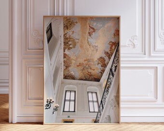 May include: A white and gold staircase with a painted ceiling depicting a scene of angels and clouds. The ceiling is painted in shades of brown, gold, and white. The staircase has a black wrought iron railing.
