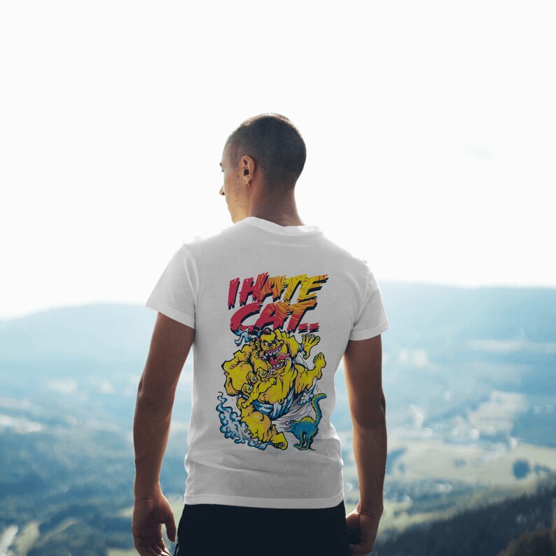 May include: White t-shirt with a graphic print of a yellow monster with the text "I HATE CAT" in red and yellow letters.