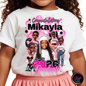 Peut inclure: T-shirt blanc avec un motif de remise de diplôme. Il présente le nom "Mikayla", des illustrations de poupées, des ballons roses et le texte "Class of 2026 Graduate" en rose.