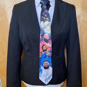 May include: A black blazer worn over a white collared shirt with a necktie featuring a graphic print of the artist Rod Wave. The tie displays multiple images of the artist, the text "Don't Look Down," and "Rod Wave" in blue script at the bottom.