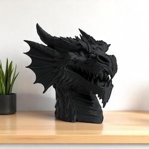 May include: A black dragon head sculpture with detailed scales, horns, and sharp teeth. The dragon head is a decorative item, perfect for fantasy enthusiasts. The sculpture is placed on a wooden surface.
