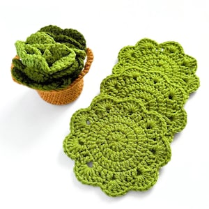 May include: Set of four green crocheted coasters with scalloped edges. The coasters are stacked on top of each other.