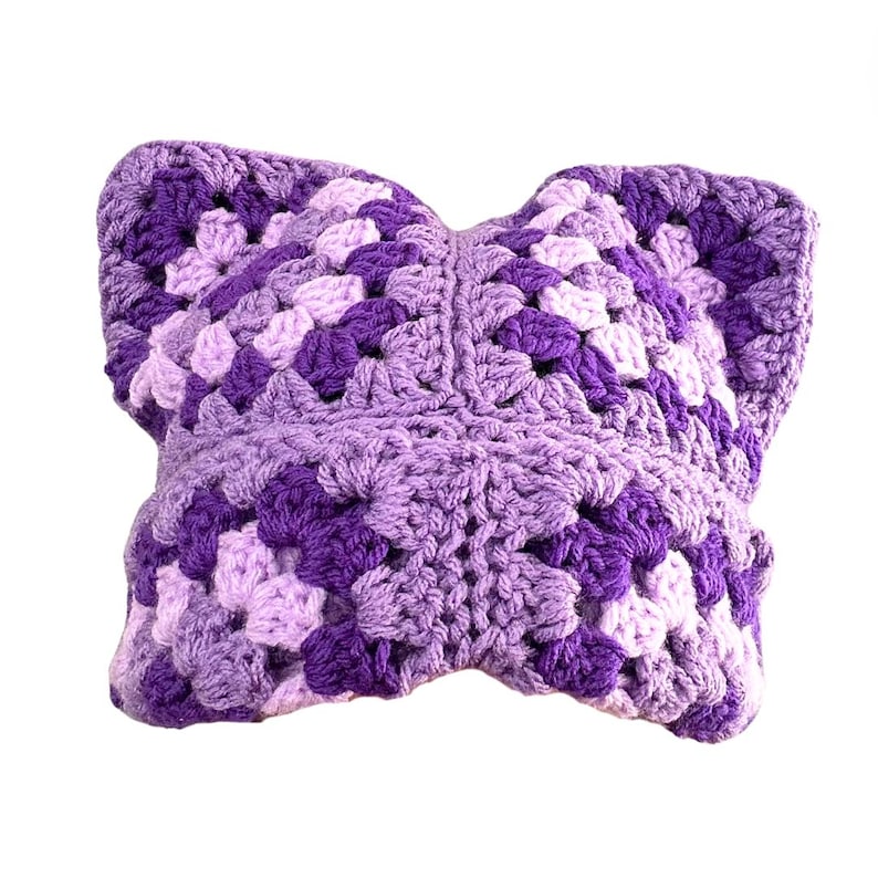 May include: A purple and lavender crocheted pillow with a square pattern.