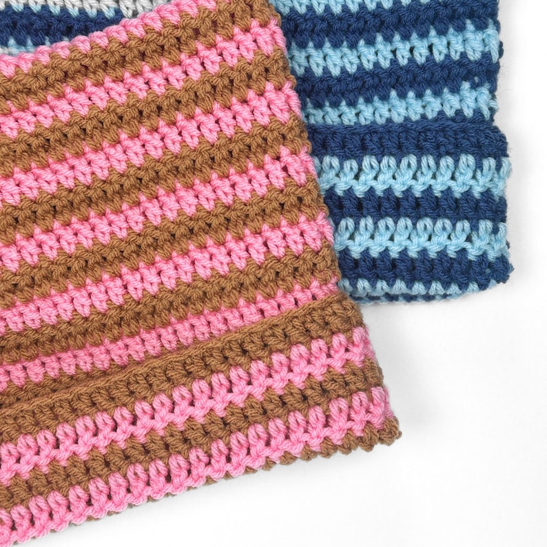 Op de afbeelding: Twee gebreide gestreepte mutsen, een in bruin en roze, de andere in blauw en lichtblauw.