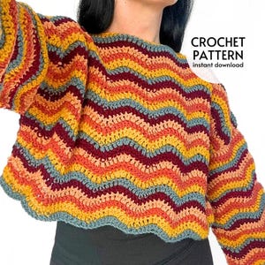 May include: A colorful crochet sweater with a chevron pattern in shades of yellow, orange, red, and blue. The sweater has long sleeves and a cropped fit. The text "CROCHET PATTERN instant download" is visible.