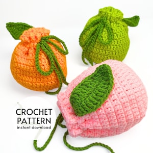 May include: Three crocheted drawstring bags in the shape of fruit. The bags are orange, pink, and green. Each bag has a green crocheted leaf attached.