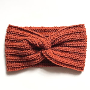 May include: A rust-colored crocheted headband with a twisted knot design.