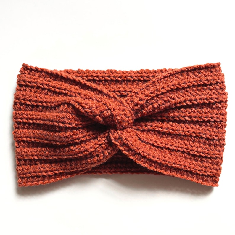May include: A rust-colored crocheted headband with a twisted knot design.