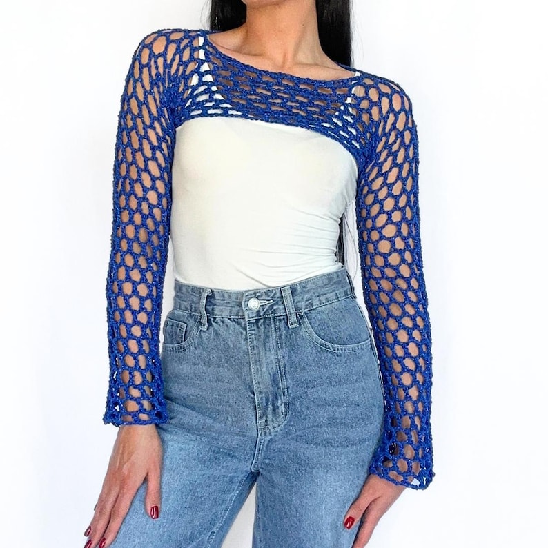 May include: A royal blue crochet top with long sleeves and a wide, open neckline. The top is made of a lightweight, airy fabric and has a delicate, open-weave design.