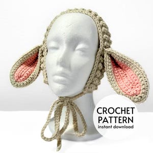 May include: Crochet pattern for a beige and pink lamb hat with floppy ears. The pattern is available for instant download.