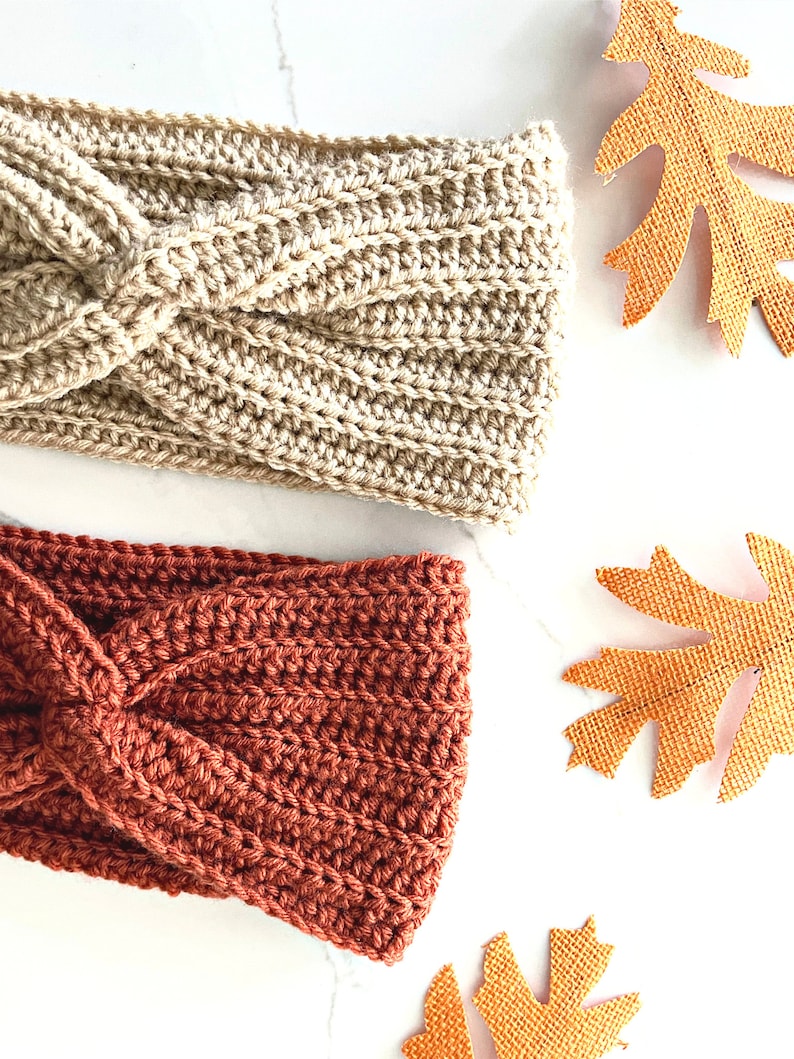 May include: Two crocheted headbands, one in a light brown color and one in a burnt orange color. Both headbands have a twisted knot design.