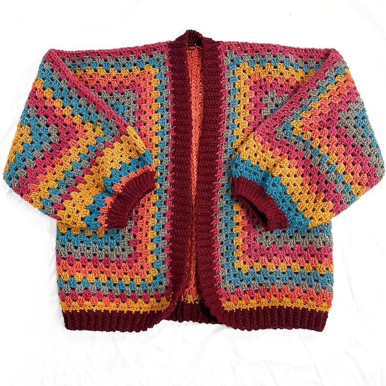May include: A colorful crocheted cardigan with a striped pattern in shades of burgundy, orange, yellow, blue, and gray. The cardigan has a long, open front and long sleeves.