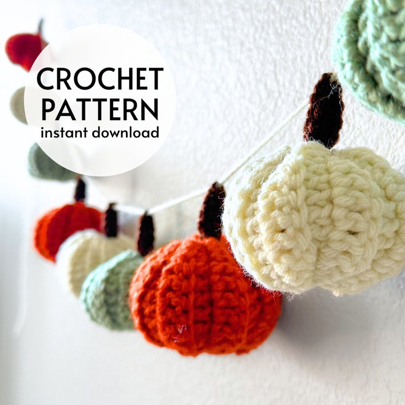 K&ouml;nnte beinhalten: Eine Girlande aus kleinen, geh&auml;kelten K&uuml;rbissen in Orange, Creme und Salbeigr&uuml;n, jeweils mit einem dunkelbraunen Stiel, aufgereiht an einer wei&szlig;en Schnur. Der Text CROCHET PATTERN instant download ist links im Bild eingeblendet.