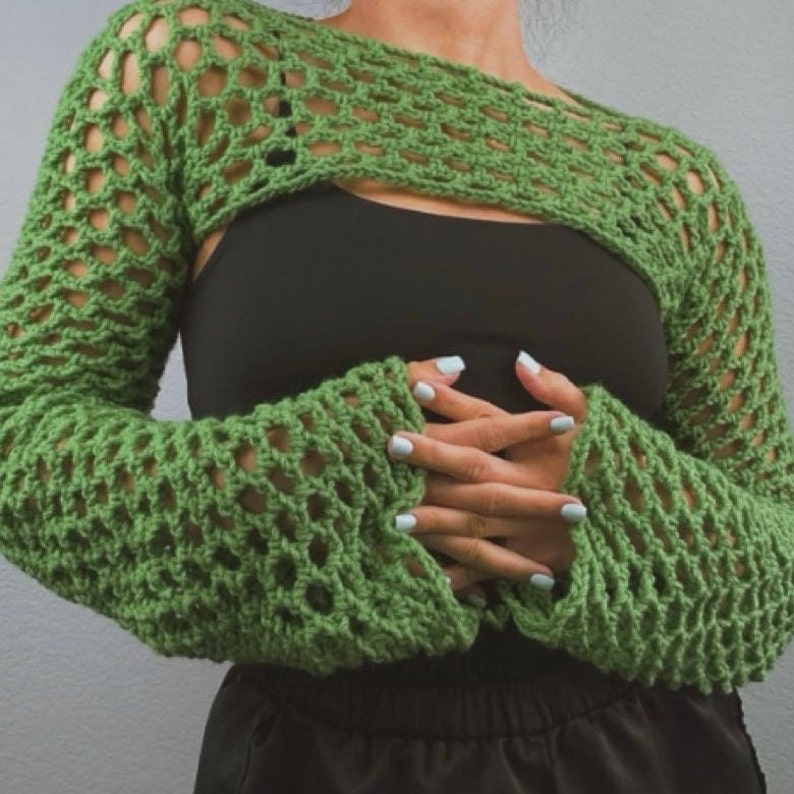 May include: Green crochet crop top with long sleeves and a loose, open-weave design. The top is cropped at the waist and has a relaxed fit.