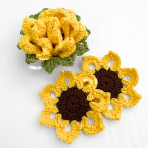 Peut inclure: Deux tournesols en crochet avec des centres marrons et des p&eacute;tales jaunes. Un plus petit tournesol en crochet avec des feuilles vertes est &eacute;galement repr&eacute;sent&eacute;.