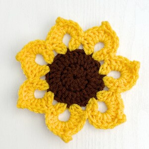 Peut inclure: Un tournesol crochet&eacute; avec un centre brun et des p&eacute;tales jaunes. Le tournesol est fait de fil et a un aspect textur&eacute; et fait main.