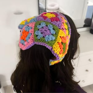 Puede incluir: Una diadema de crochet colorida con un patr&oacute;n de cuadrados de la abuela en tonos de rosa, morado, azul, verde, amarillo y naranja.