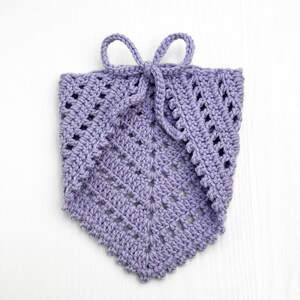 Puede incluir: Una bufanda de cuello de ganchillo de color lavanda con un lazo. La bufanda tiene un patr&oacute;n delicado y de encaje.