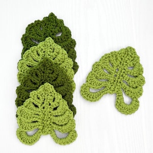 May include: Five crocheted green leaf coasters with a single leaf coaster in the same style.