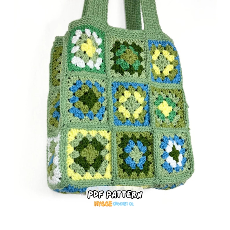 May include: A tote bag constructed from multiple crocheted granny squares in shades of sage green, forest green, yellow, white, and blue. The bag features two integrated handles and includes the text PDF PATTERN HYGGE CROCHET CO.
