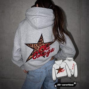 May include: A light gray hooded sweatshirt featuring a large star with a brown and black leopard print pattern on the back. The text Chi Omega is embroidered in red script across the star. A small graphic shows the hoodie design.