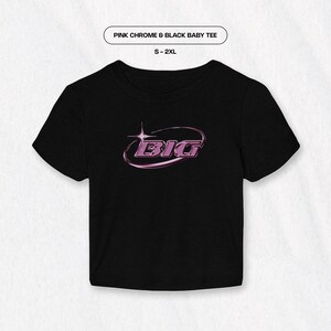May include: Black baby tee with a pink chrome "BIG" graphic in a circle with a star. The tee is available in sizes S-2XL.