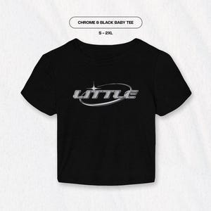 May include: Black baby tee with a silver chrome graphic that says "LITTLE" in a rounded oval shape.