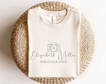 May include: A white t-shirt with a black camera and text that reads "Elizabeth Miller PHOTOGRAPHY" printed on the front.