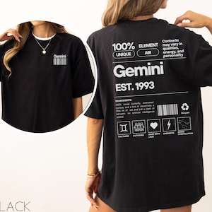 Op de afbeelding: Zwart oversized T-shirt met een witte grafische print van het sterrenbeeld Tweelingen, de tekst "Gemini Est. 1993" en een lijst met kenmerken die aan het teken zijn gekoppeld. De grafiek bevat ook een barcode en een recycle-symbool.