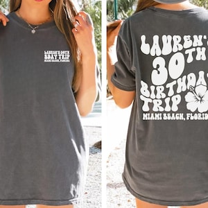 May include: A gray t-shirt with white text that says "Lauren's 30th Birthday Trip Miami Beach, Florida" on the back. The front of the shirt has the text "Lauren's 30th Bday Trip Miami Beach, Florida".