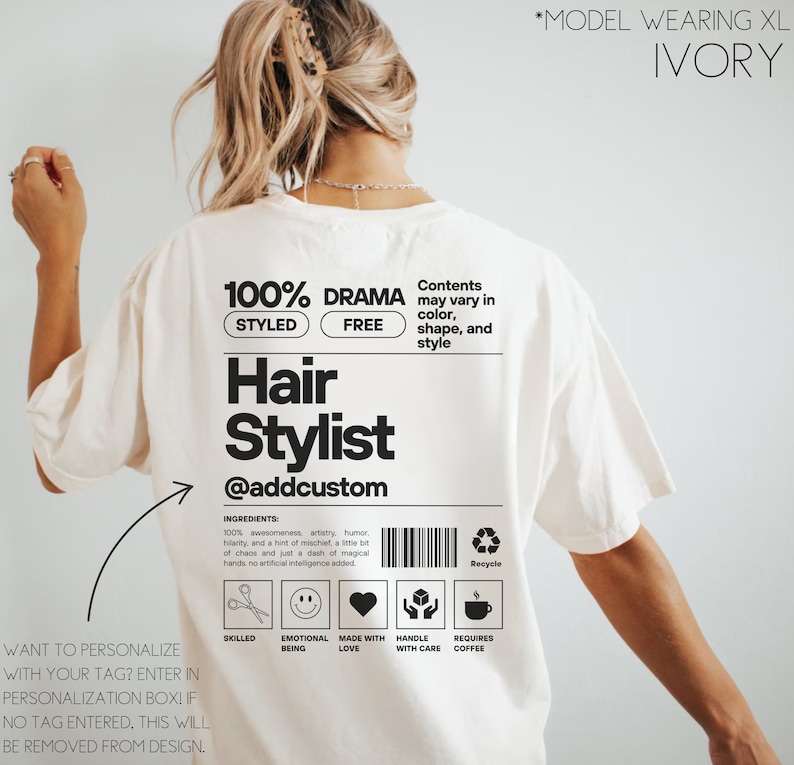 May include: White t-shirt with a black graphic design that says "100% Drama Styled Free Hair Stylist @addcustom". The graphic also includes a barcode, a recycle symbol, and icons for skilled, emotional being, made with love, handle with care, and requires coffee.