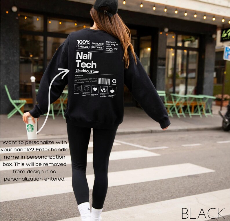 May include: Black crewneck sweatshirt with white text that reads "Nail Tech @addcustom" and a graphic on the back. The sweatshirt also has the words "100% Manicure Skilled Specialist" printed on it. The model is wearing black leggings and a black cap.
