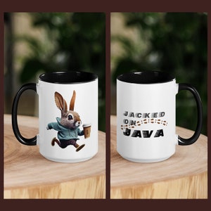 Peut inclure: Une tasse en céramique blanche avec un bord et une poignée noirs. La tasse représente un lapin de dessin animé portant un sweat-shirt bleu et tenant une tasse de café. Le texte "JACKED ON JAVA" est imprimé sur l'autre côté de la tasse.