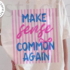 May include: Cream-colored t-shirt with the text "MAKE sense COMMON AGAIN" in blue and pink, set against a striped background. The design includes a bow graphic. The shirt is part of a digital download.