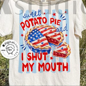 May include: Cream-colored t-shirt with a patriotic sweet potato pie graphic. The design features a pie with a star-spangled crust and red filling, along with the text "Sweet Potato Pie and I Shut My Mouth."