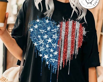 Könnte beinhalten: Ein schwarzes T-Shirt mit einem glitzernden rot-weiß-blauen Herz-förmigen amerikanischen Flaggen-Design. Das Design ist mit Glitzer besetzt, was einen einzigartigen und patriotischen Look erzeugt. "Digitaler Download" und "Designed by Kstudio" sind auf dem Shirt aufgedruckt.