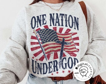 Puede incluir: Una sudadera gris claro con un gráfico desgastado de la bandera estadounidense, una cruz y el texto "ONE NATION UNDER GOD". El diseño utiliza colores rojo, blanco y azul. Las palabras "digital download" están en la parte inferior.