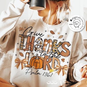 May include: Cream-colored sweatshirt with the text "Give Thanks to the Lord" in a fall-themed design. The design includes a pumpkin, bows, and leaves. The text "Psalm 136:1" is also included. The words "digital download" are at the bottom.
