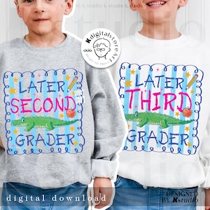 Op de afbeelding: Twee sweatshirts voor kinderen. E&eacute;n is grijs, de andere wit. Beide hebben een kleurrijke afbeelding met de woorden "Later Second Grader" en "Later Third Grader". Elk ontwerp bevat een groene alligator, een appel en een potlood.