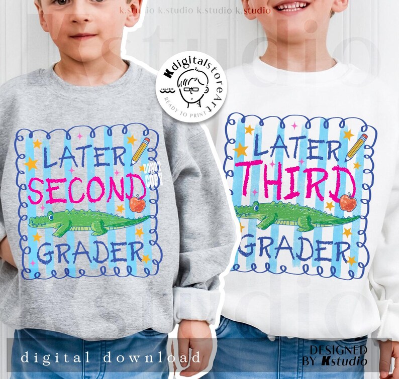 Op de afbeelding: Twee sweatshirts voor kinderen. E&eacute;n is grijs, de andere wit. Beide hebben een kleurrijke afbeelding met de woorden "Later Second Grader" en "Later Third Grader". Elk ontwerp bevat een groene alligator, een appel en een potlood.